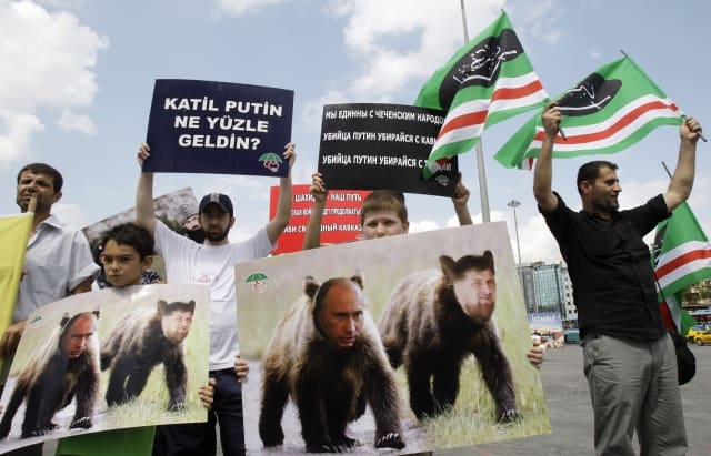 Pro-Chechen demonstrator hold poster of bears with faces of Russian Prime Minister Vladimir Putin, left and Chechen President Ramzan Kadyrov as they protest against Putin's visit to Turkey, in Istanbul, Turkey, Thursday, Aug. 6, 2009. (AP Photo/Ibrahim Usta) =@=