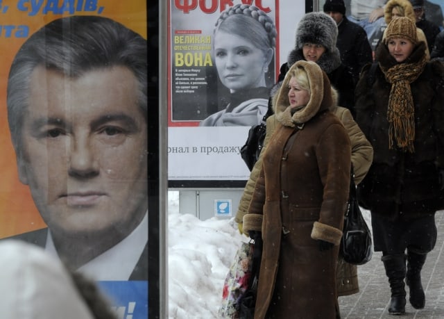 People walk past billboards for presidential candidates Viktor Yushchenko, left, and Yulia Timoshenko, center, in Kiev, Ukraine, Monday, Jan. 4, 2010. The first round of voting in Ukraine's presidential election is schedule for Jan.17, 2010. (AP Photo / Sergei Chuzavkov)