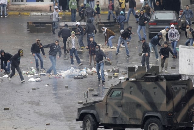 Turkish Kurdish youths throw stones at an armored police vehicle during a protest to mark the 10th anniversary of the capture of Kurdish rebel leader Abdullah Ocalan, in Istanbul, Turkey, Sunday, Feb. 15, 2009. Turkish police across the country broke up demonstrations by Kurds marking the 10th anniversary of the capture of Ocalan. The leader of the Kurdistan Workers Party was captured in 1999 and is the sole inmate of an island prison. The group has expressed concern about his health and wants an end to his solitary confinement. (AP Photo/Murad Sezer) =@=