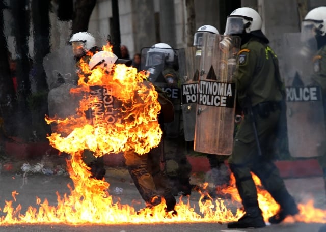 A riot policeman's clothing catches fire after demonstrators threw petrol bombs at them, as violence erupted during a march to mark the first anniversary of the police shooting of a teenager, whose death sparked massive riots, in Athens, on Sunday, Dec. 6, 2009. Clashes also broke out in Greece's second largest city, Thessaloniki. (AP photo/Dimitri Messinis)