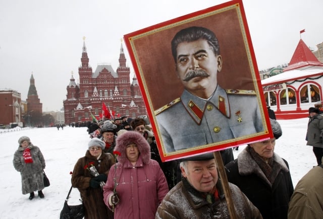 Russian Communists hold up a portrait of Soviet dictator Josef Stalin as they queue to lay flowers at his grave to mark the 130th anniversary of Stalin's birth in Red Square in Moscow, Russia, Monday, Dec. 21, 2009. (AP Photo/Ivan Sekretarev)