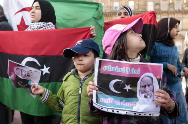 Anti-Gaddafi protesters hold up banners in George Square, Glasgow, as violence continues to rage in Libya