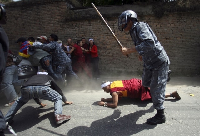 A Tibetan monk falls down as policemen baton charge scores of exiled Tibetan monks, nuns and people during a protest rally against China outside the Visa section of Chinese Embassy in Katmandu, Nepal, Sunday March 30, 2008. (AP Photo/Saurabh Das) =@=