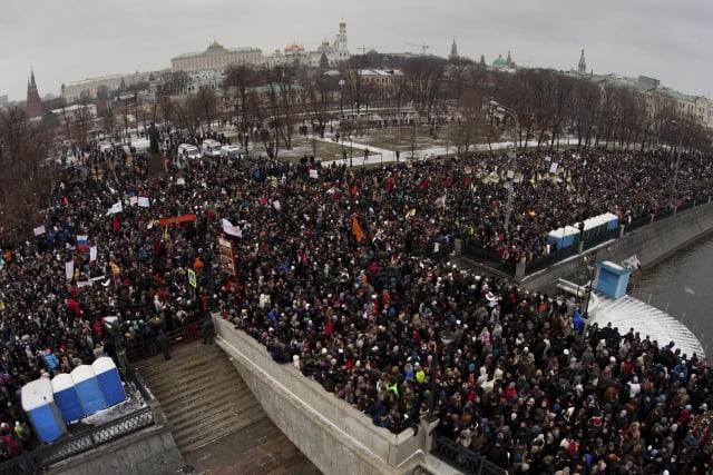 In this photo taken Saturday, Dec. 10, 2011, protesters gather to protest near the Kremlin, background, against alleged vote rigging in Russia's parliamentary elections in Moscow, Russia. Tens of thousands of people held the largest anti-government protests that post-Soviet Russia has ever seen to criticize electoral fraud and demand an end to Vladimir Putin's rule. (AP Photo/Ridus, Dmitriy Chistoprudov) =@=