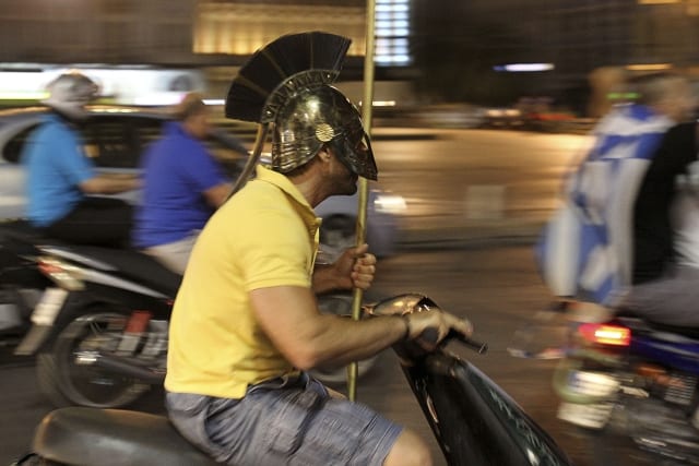 A Greek man wearing a replica of an ancient warrior's helmet drives a motorcycles around Omonia Square to celebrate the country's win against Russia in the Euro 2012 soccer tournament in central Athens, late Saturday, June 16, 2012. (AP Photo/Petros Karadjias)