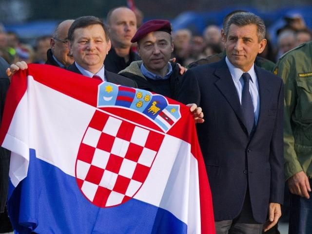 Croatian Gen. Ante Gotovina, right and Gen. Mladen Markac hold the Croatian flag upon their arrival to the airport in Zagreb, Croatia, Friday, Nov. 16, 2012. The Yugoslav war crimes tribunal overturned the convictions of the two Croat generals on Friday for murdering and illegally expelling Serb civilians in a 1995 military blitz, and ordered both men to be freed immediately. (AP Photo/Nikola Solic)